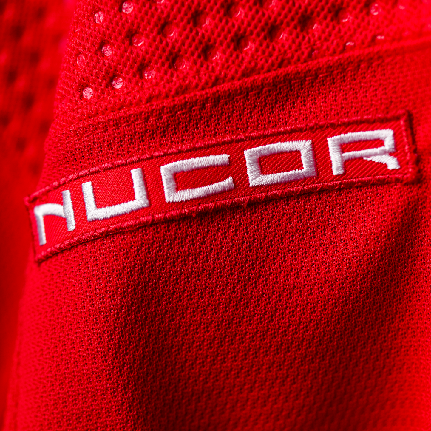 Red patch with NUCOR logo in white lettering