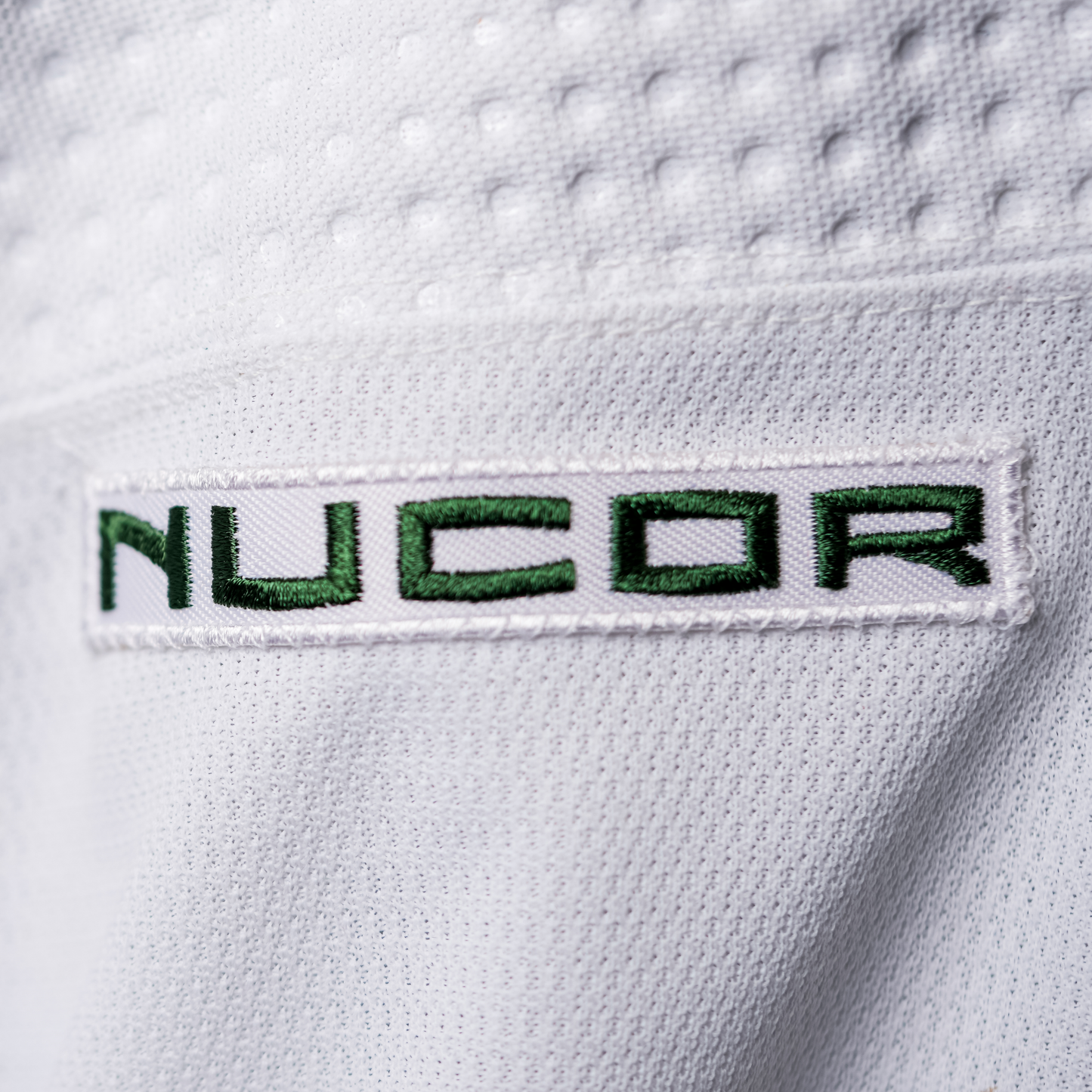 White patch with NUCOR logo in green lettering