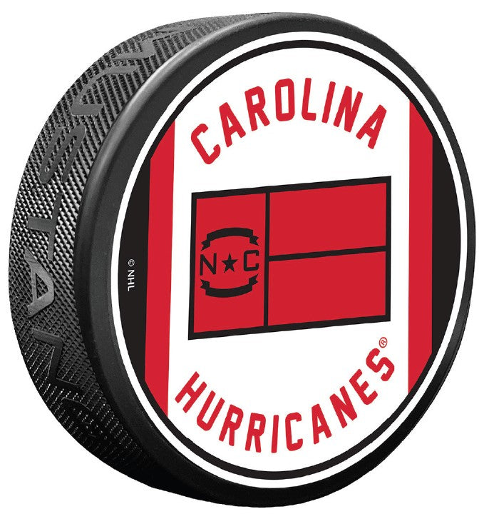 White puck, red/black trim, "CAROLINA HURRICANES" in red arched around Jersey Flag logo