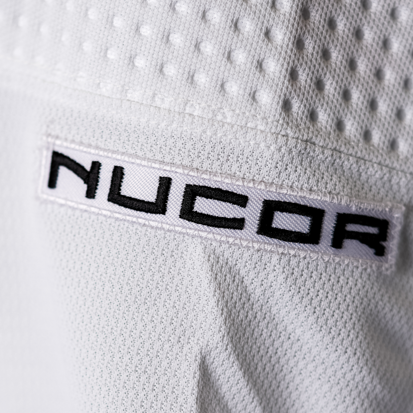 White patch with NUCOR logo in black lettering