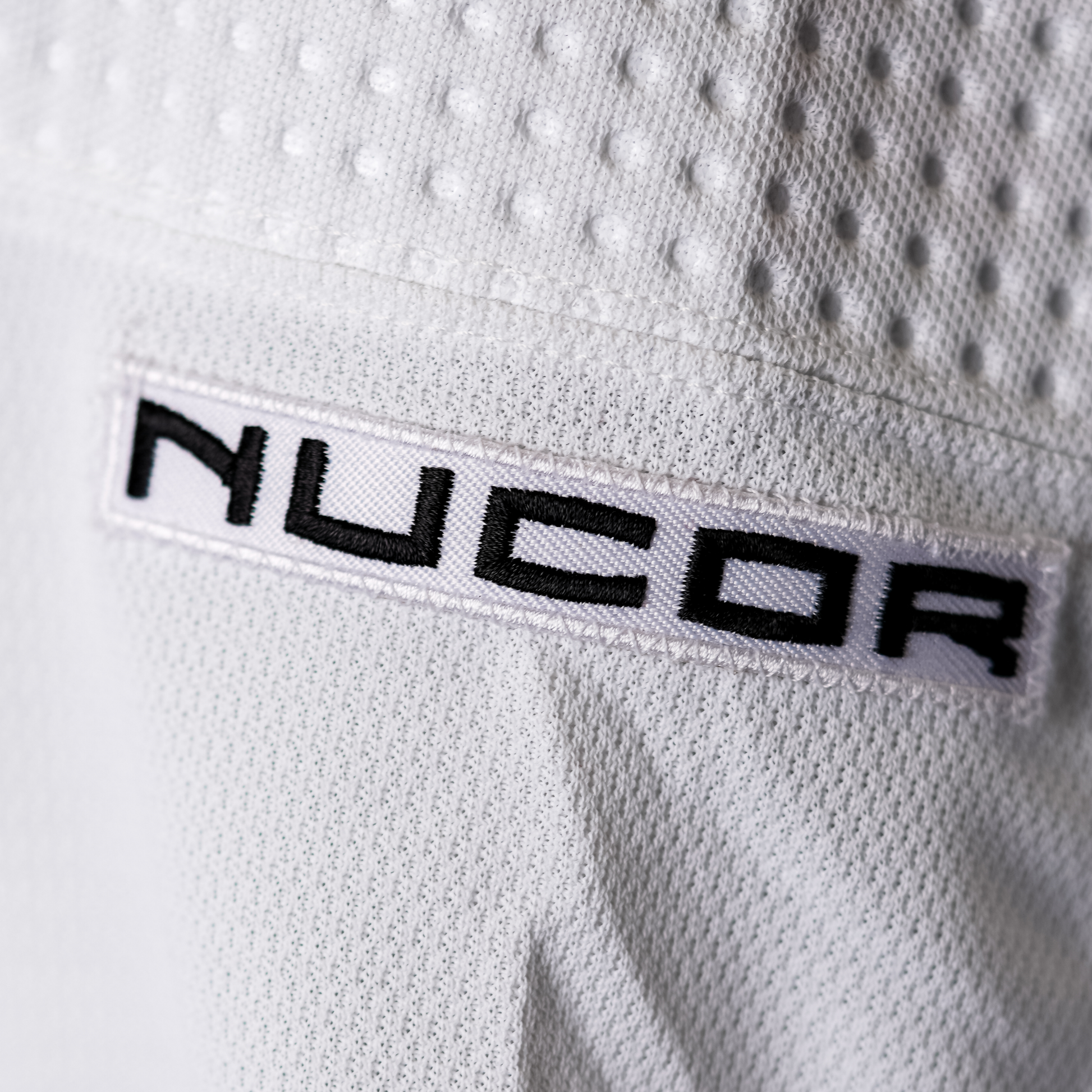 White patch with NUCOR logo in black lettering