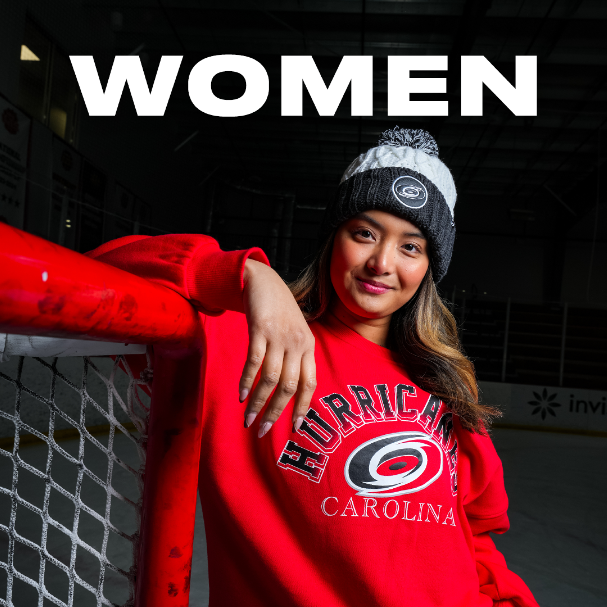 "WOMEN" in white text over a model wearing Hurricanes merch leaning on a hockey net