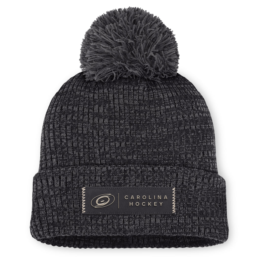 Front: Black cuffed acrylic beanie with grey pom, rectangular "CAROLINA HOCKEY" patch on cuff in black/beige