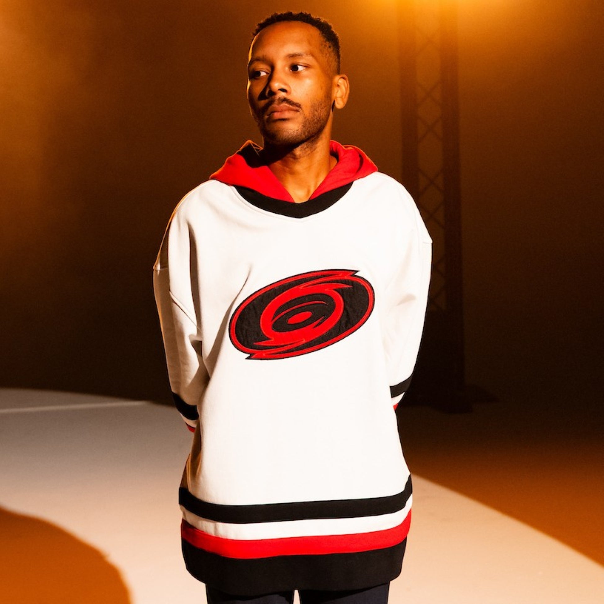 White hoodie with red/black trim, being worn by a model