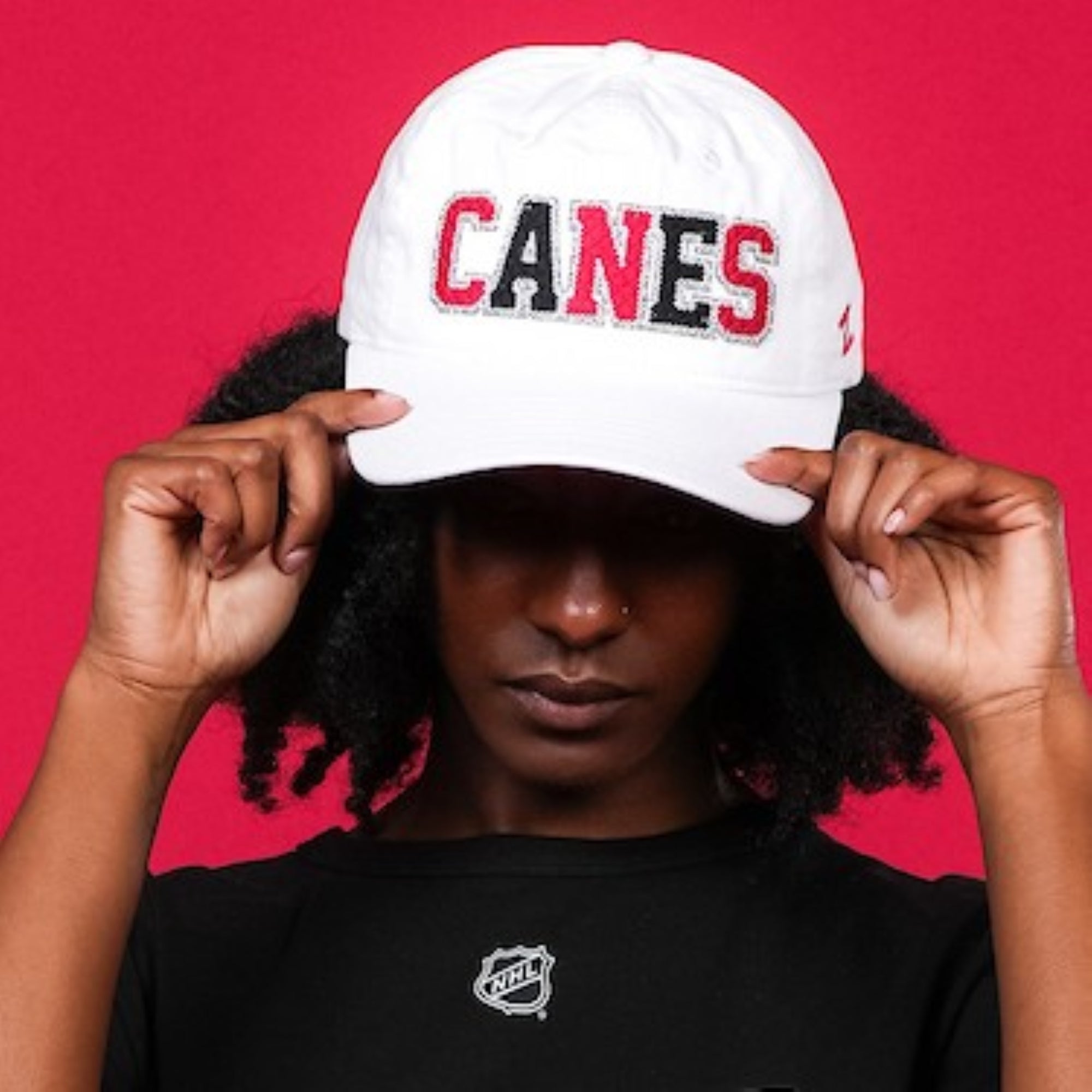 The hat being worn by a model in front of a red backdrop