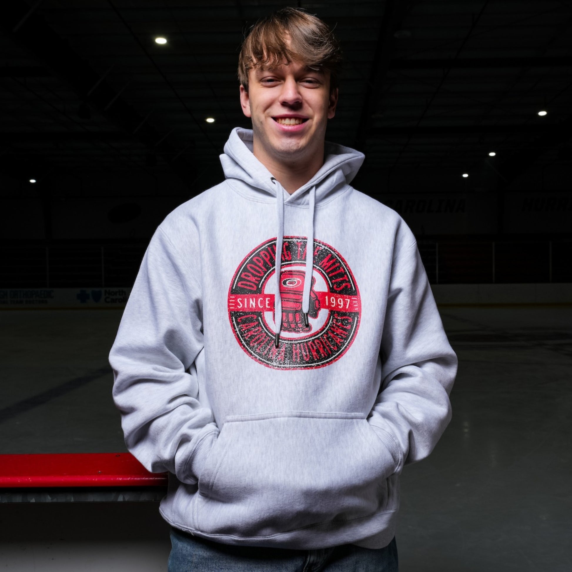 The hoodie being worn by a model while standing on a hockey bench