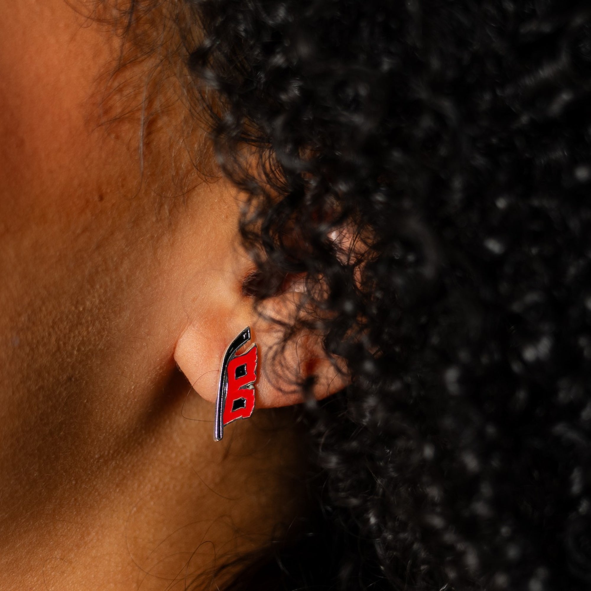 The Flags logo earring on an ear