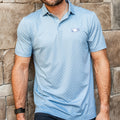 Light blue polo with dark blue pattern, white Pucky Whalers logo on left chest