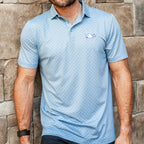 Light blue polo with dark blue pattern, white Pucky Whalers logo on left chest