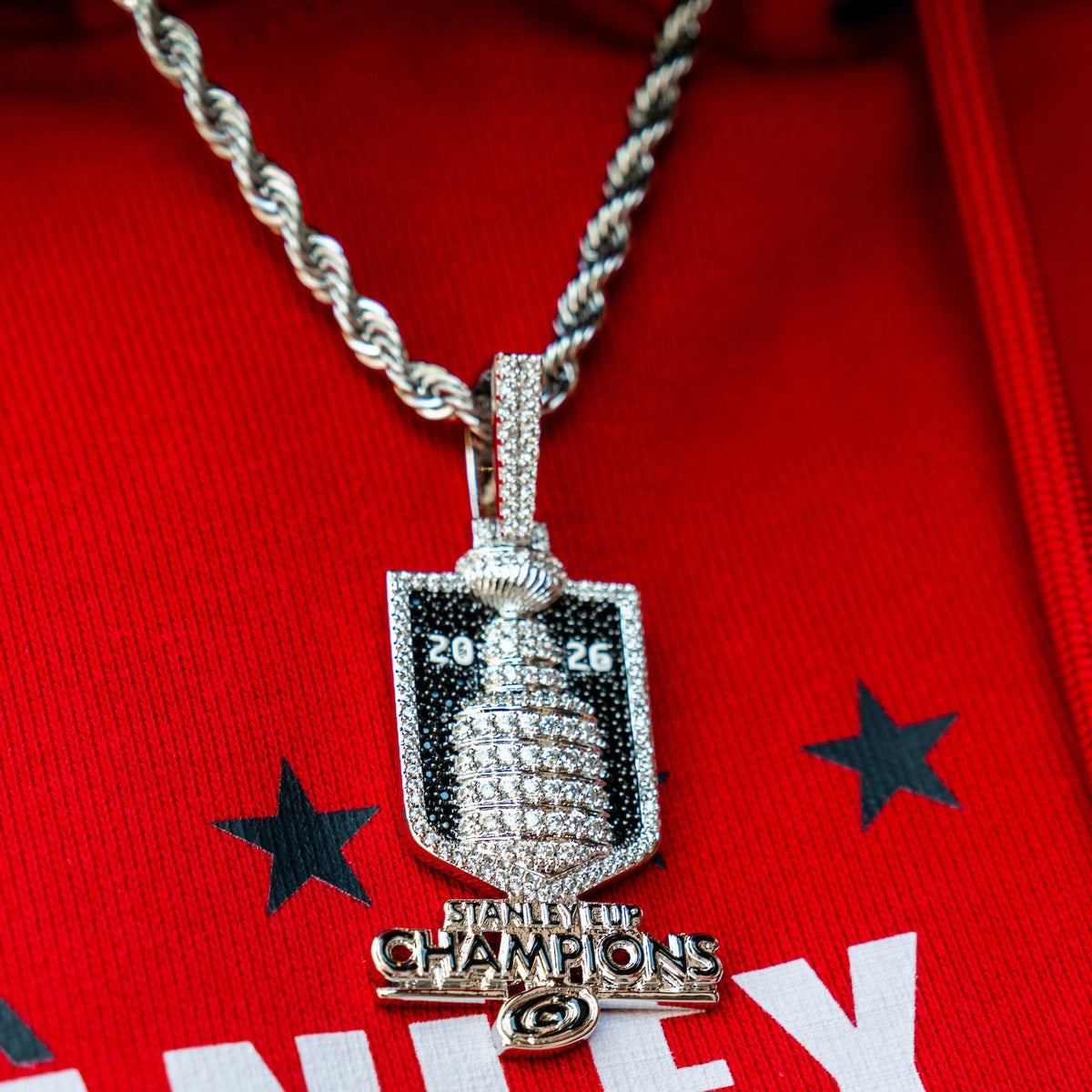 The chain and pendant being worn on top of a red hoodie