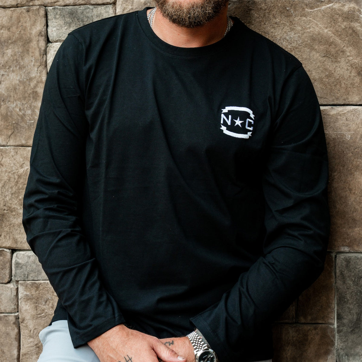 Front: Black longsleeve, white 'NC' insignia on left chest