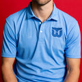 Front: Blue polo with light blue pattern, blue Whalers Tail logo on left chest