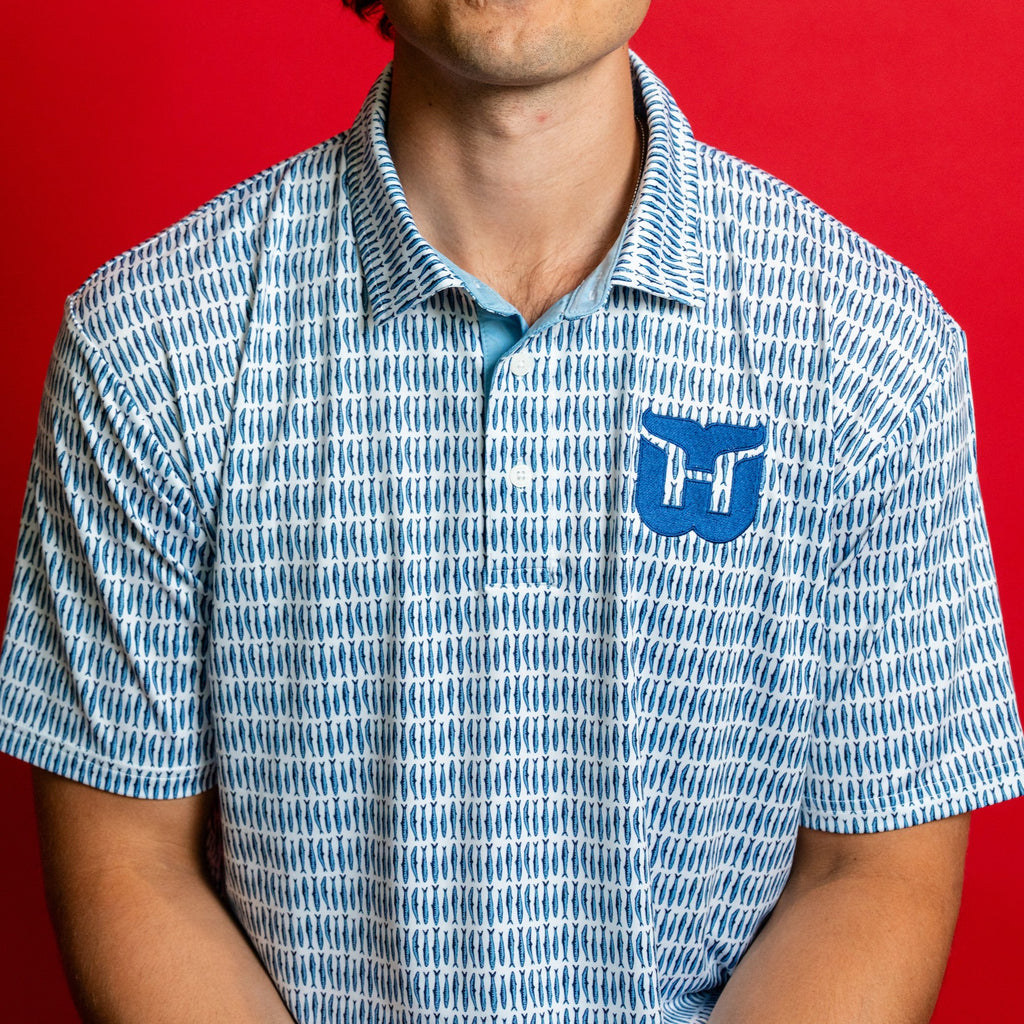 White polo with pattern of blue Sardines; blue Whalers Tail logo on left chest