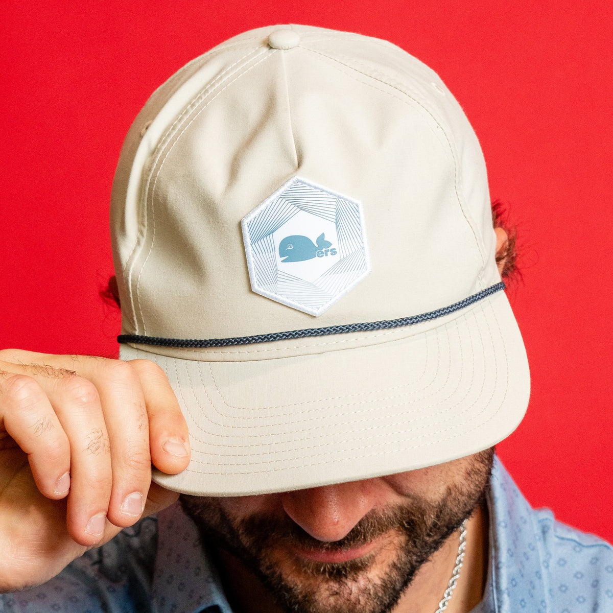 Biege hat, blue rope on brim; white hexogonal patch with blue pattern on front, Pucky logo in center
