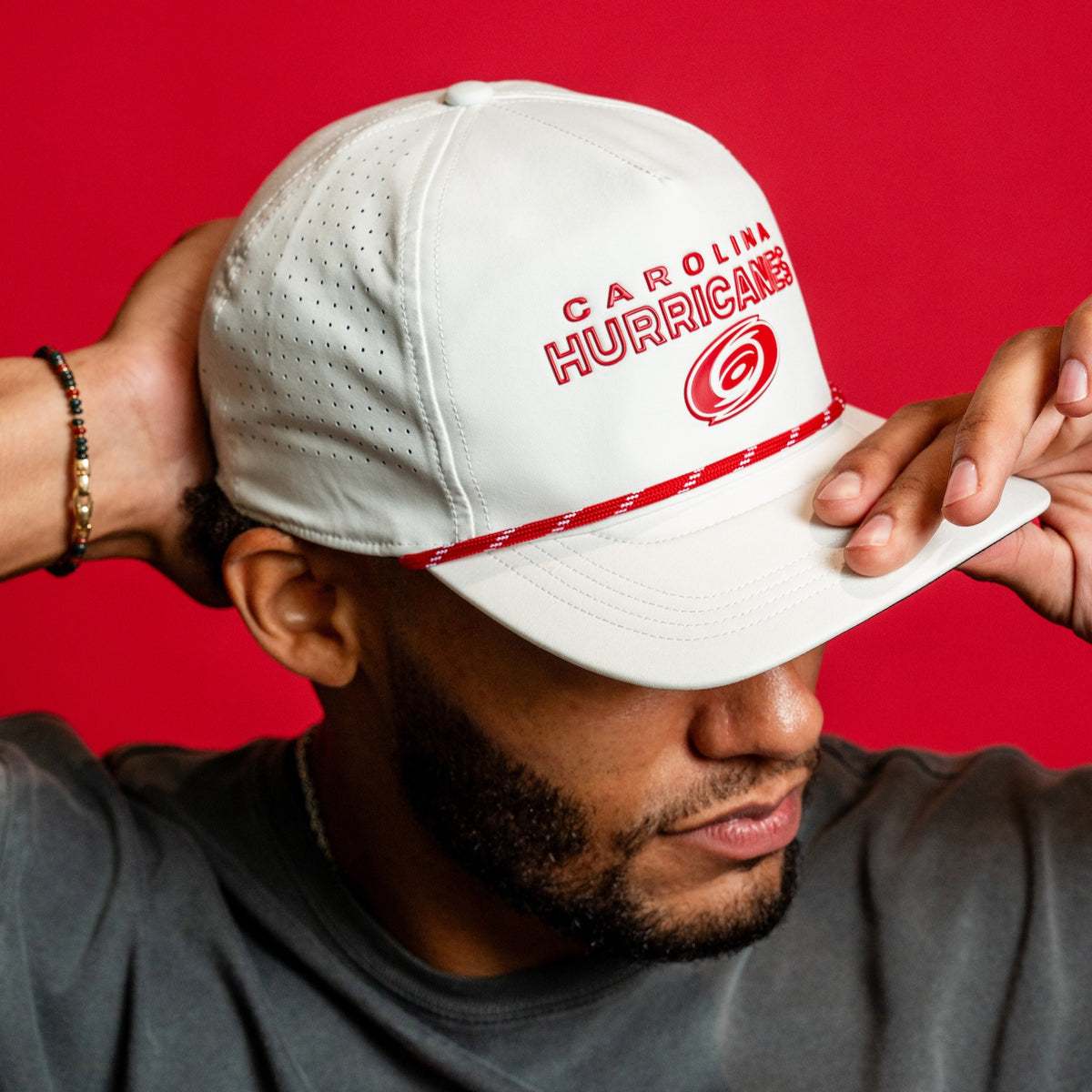 The hat being worn by Hurricanes defenseman K'Andre Miller in front of a red background