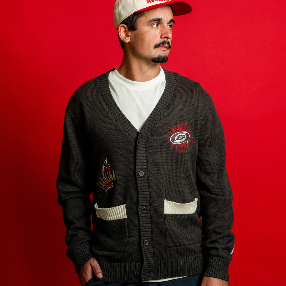 The sweater being worn by Hurricanes forward Seth Jarvis in front of a red background
