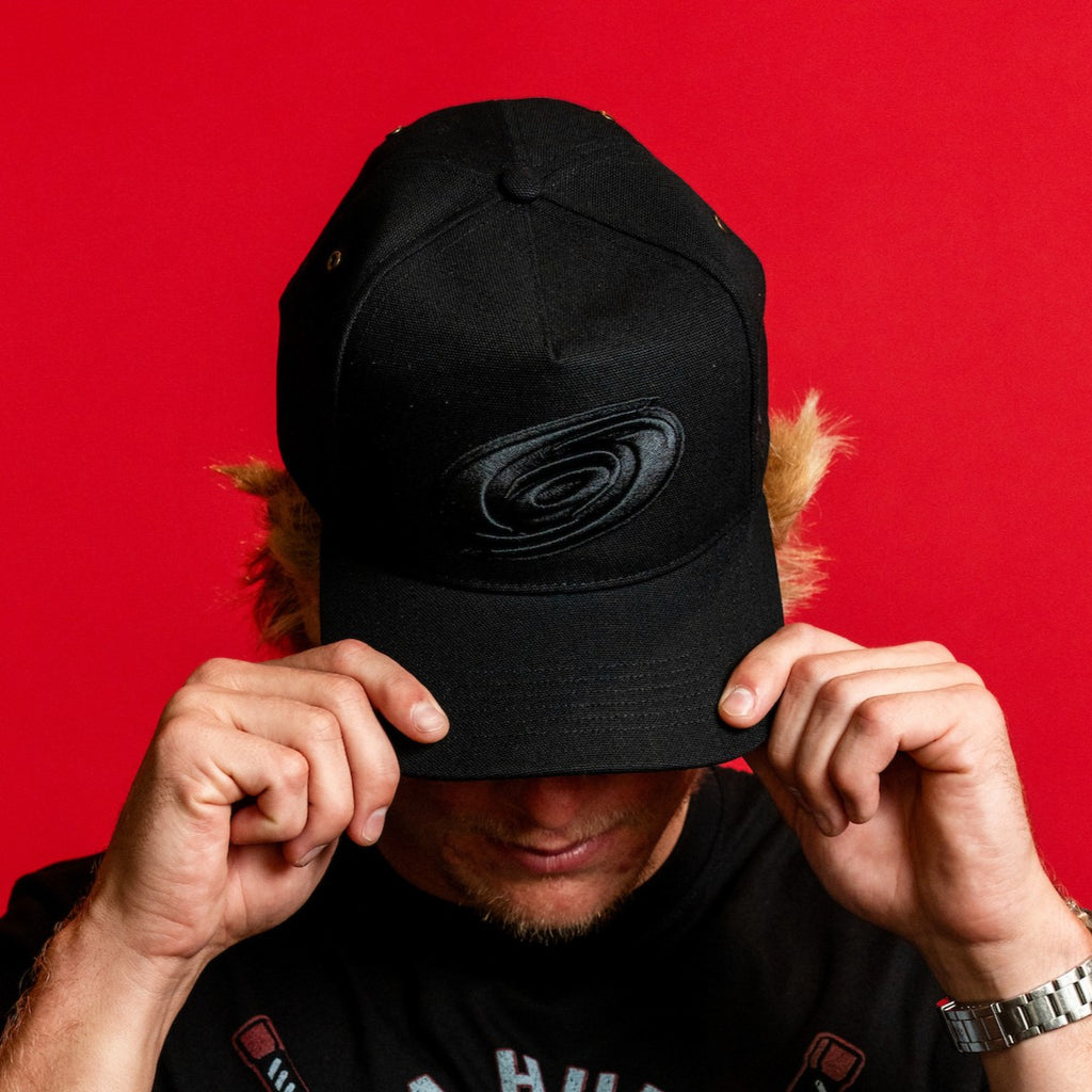 The hat being worn by Hurricanes forward Jackson Blake in front of red background