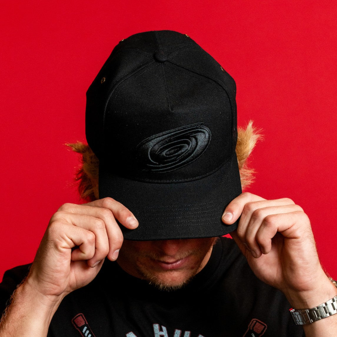 The hat being worn by Hurricanes forward Jackson Blake in front of red background