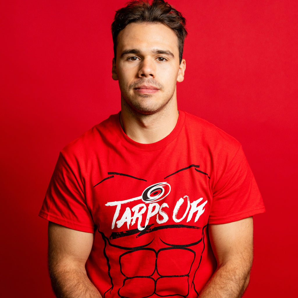 The tee being worn by Hurricanes forward Logan Stankoven in front of red background