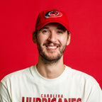 The hat being worn by Hurricanes goaltender Brandon Bussi in front of red background