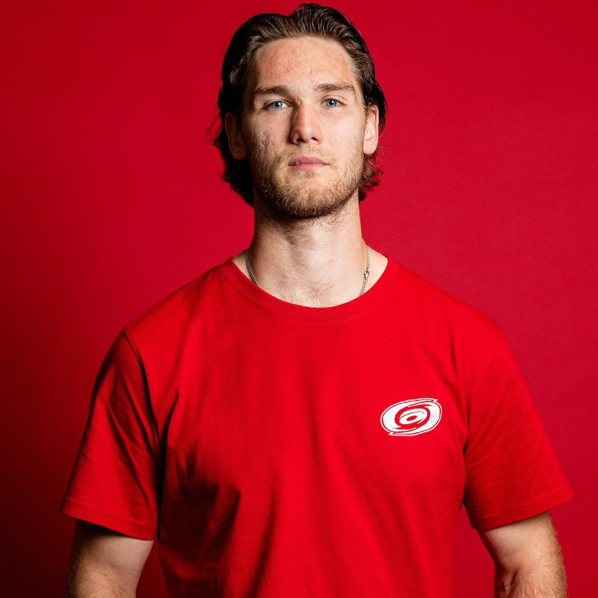 The tee being worn by Hurricanes forward Mark Jankowski in front of red background