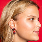 The earring being worn by a model in front of a red background
