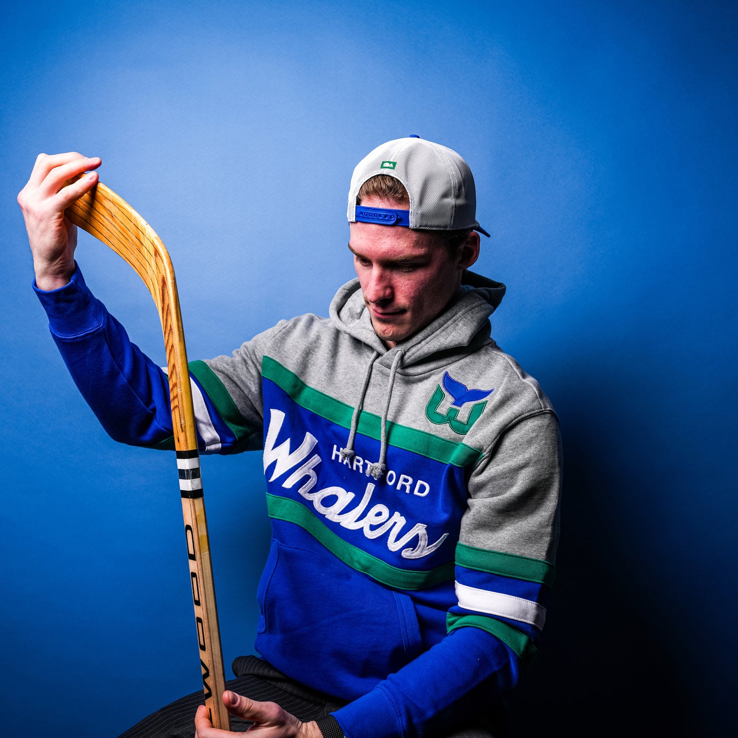 Hurricanes forward Andrei Svechnikov posing wearing the hoodie while holding wooden hockey stick