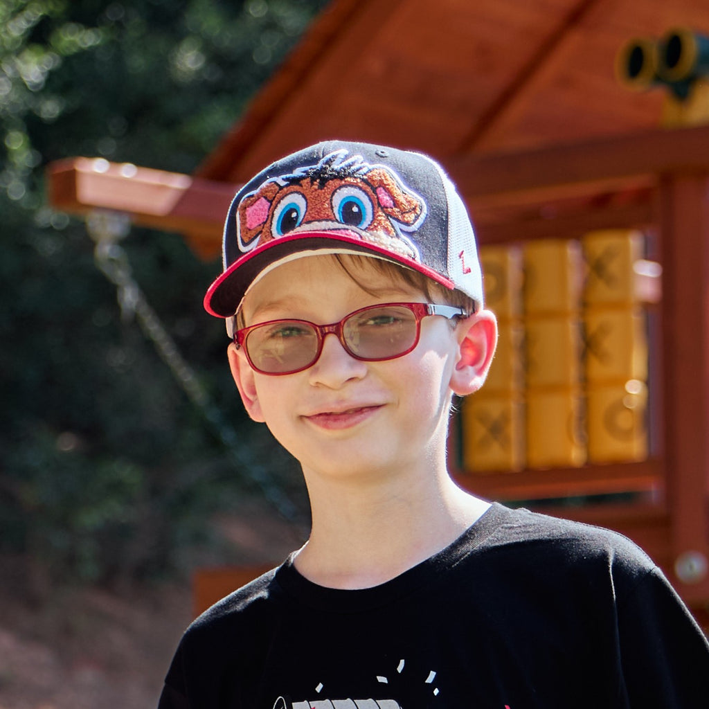The hat being worn by a model outdoors in front of a playset