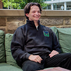 The quarter-zip being worn by a model outdoors while they sit on a couch