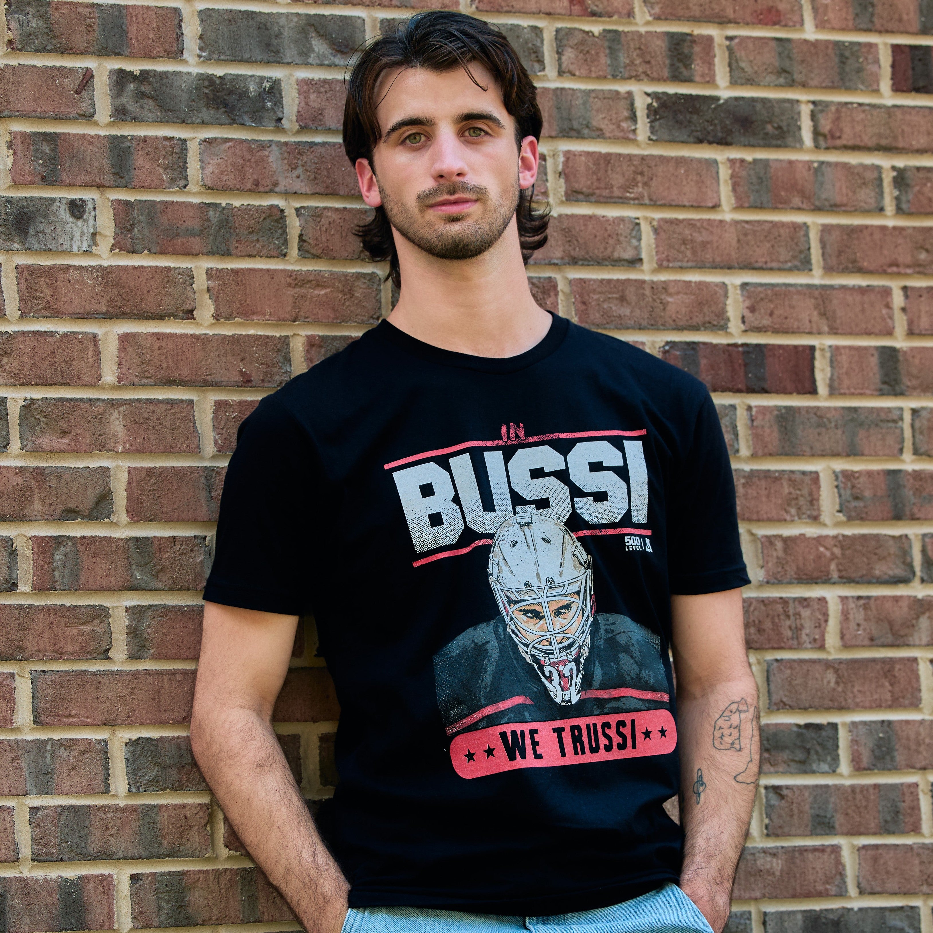 The t-shirt being worn by a model standing in front of a brick wall