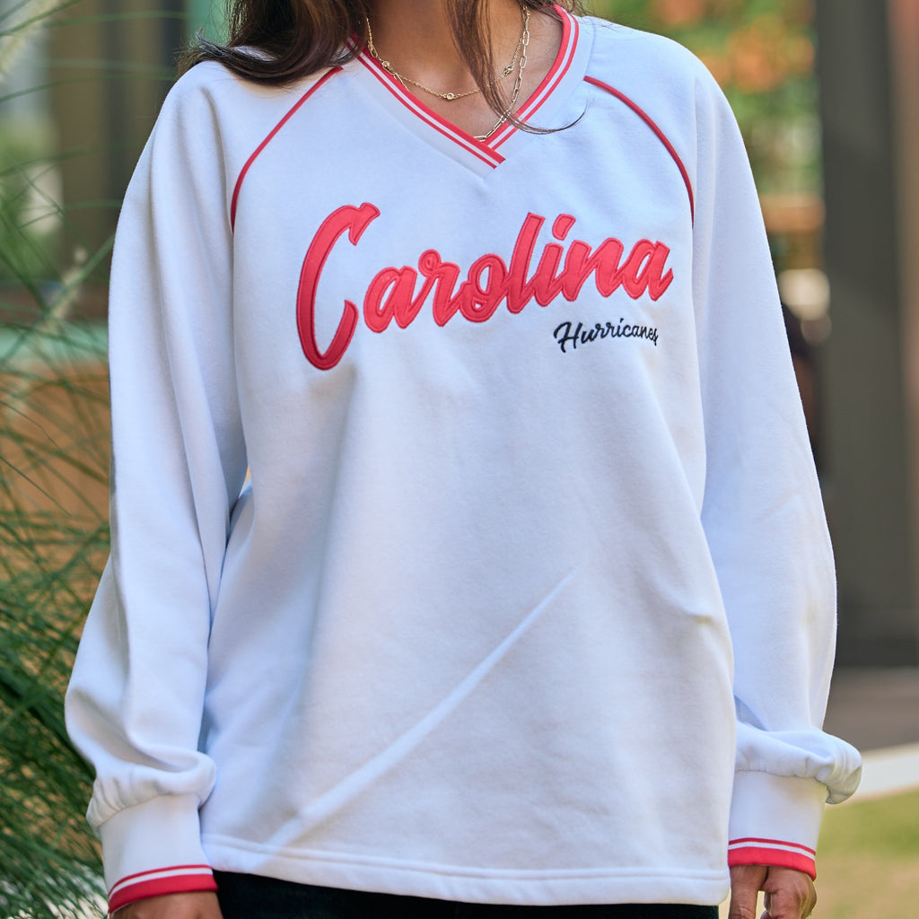 White pullover with red trim, "Carolina" in large cursive red text, "Hurricanes" in smaller black cursive across front