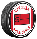 White puck, red/black trim, "CAROLINA HURRICANES" in red arched around Jersey Flag logo