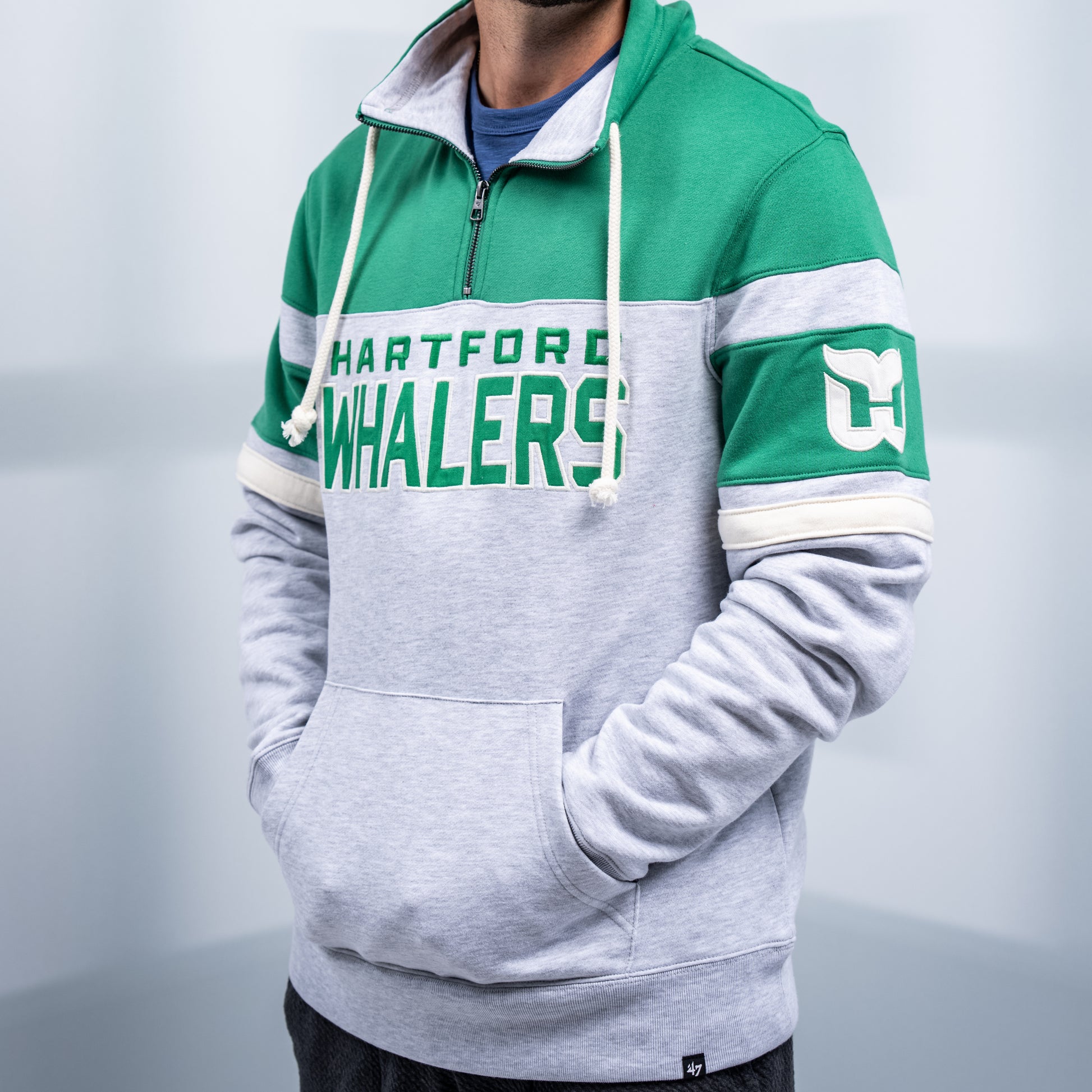 Gray quarter-zip with gray accent, collar with strings,  "Hartford Whalers" in green across chest