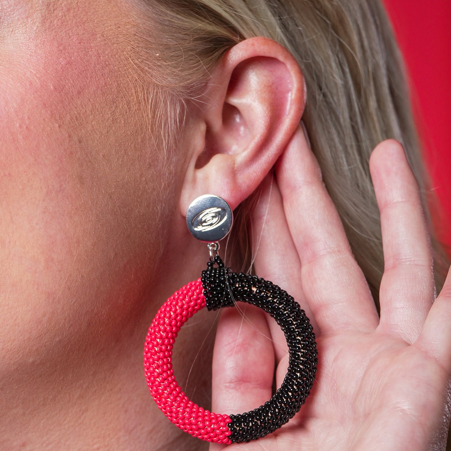 Red and black hand beaded hoop attached to silver earring finding with primary logo