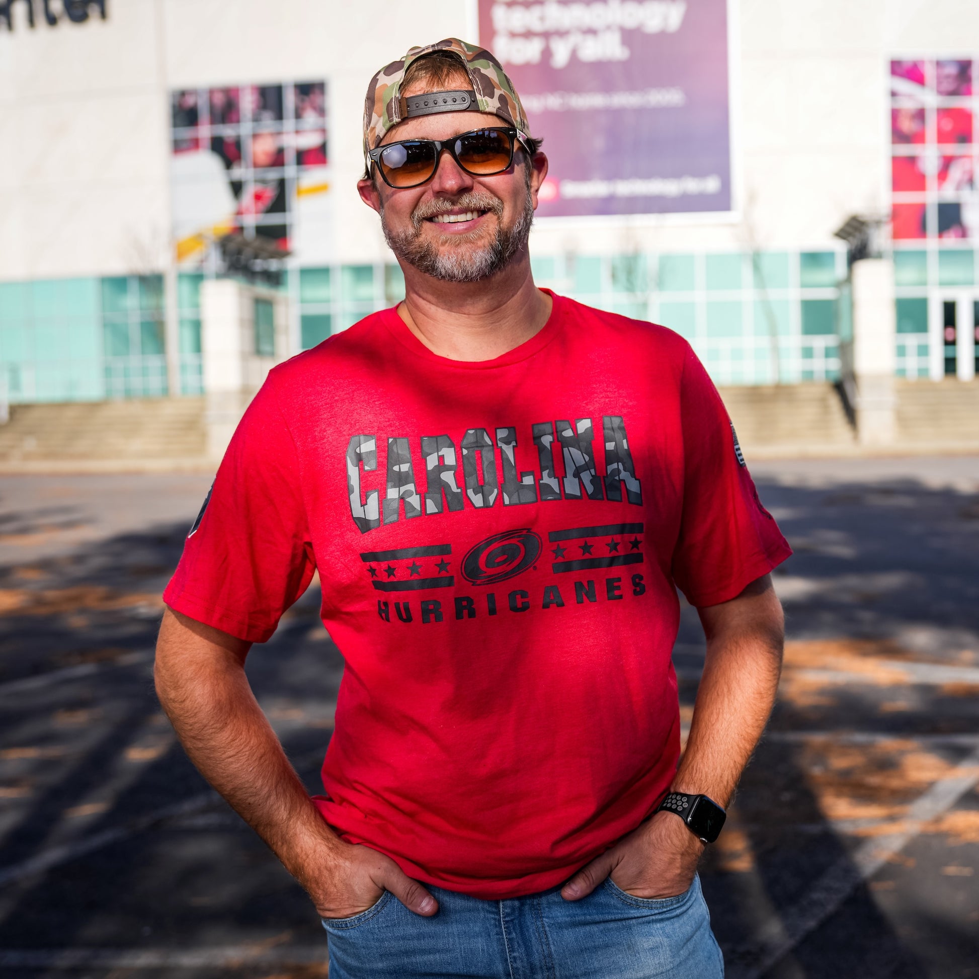 Model posing wearing the tee in front of the Lenovo Center