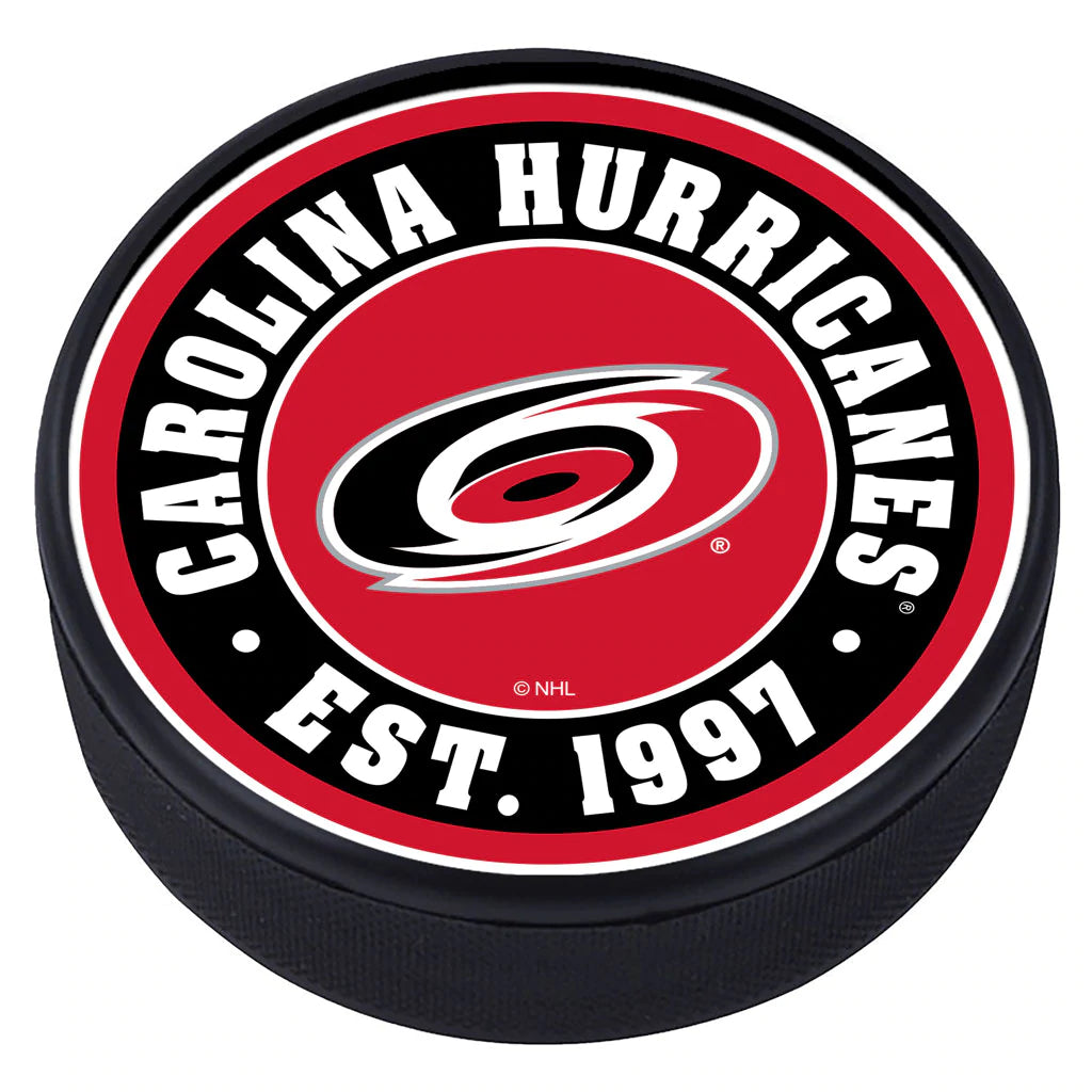 Hockey puck with the Hurricanes primary logo and the phrase "Carolina Hurricanes Est. 1997" on the outside of a red top face.