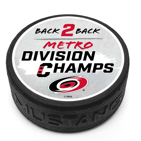Hockey puck with phrase "Back 2 Back Metro Division Champs" and the Hurricanes primary logo on a white top face. 